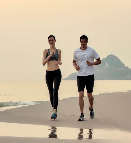 Couple running along beach near Chiva-Som Hua Hin in the morning.
