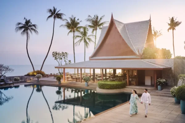 A serene Thai wellness retreat featuring a beautiful villa by the pool and surrounded by palm trees.